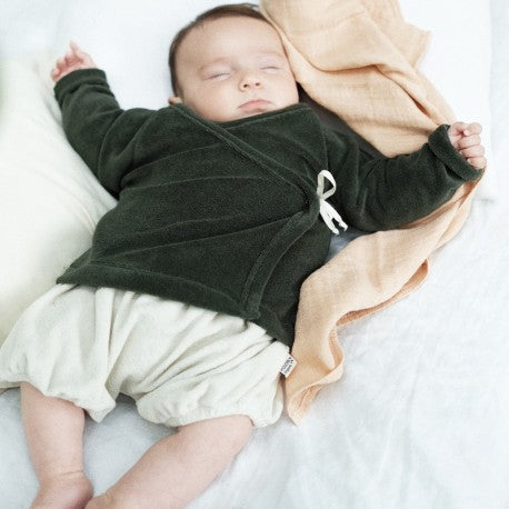Baby wearing green terry cloth top & white shorts