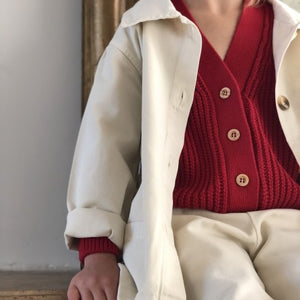 Kid in red cardigan & white jacket